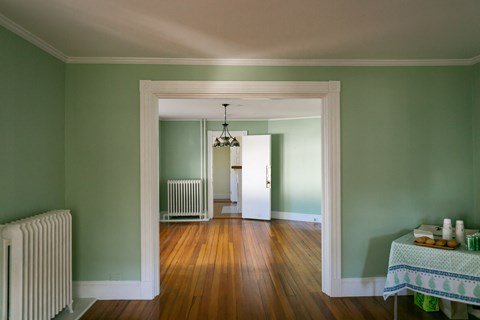 a living room and dining room with green walls and a wood floor