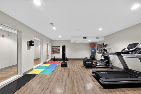A gym with a treadmill, exercise balls, and a yoga mat.