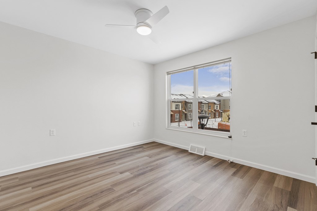 an empty living room with a large window and wooden floors