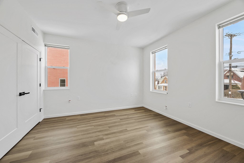 a living room with white walls and wood flooring and a white door and windows