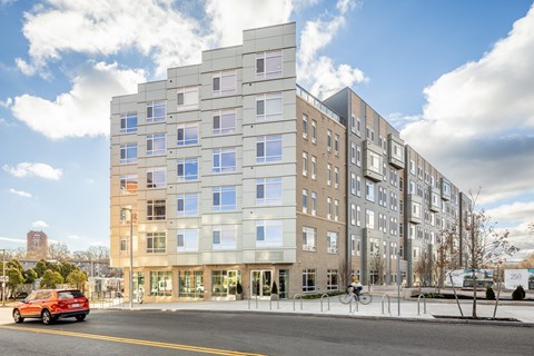 an apartment building on a city street with a red car