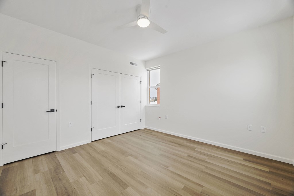 a living room with white walls and wooden floors and a window