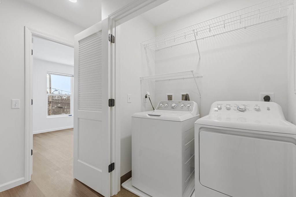 a white laundry room with two washes and a dryer