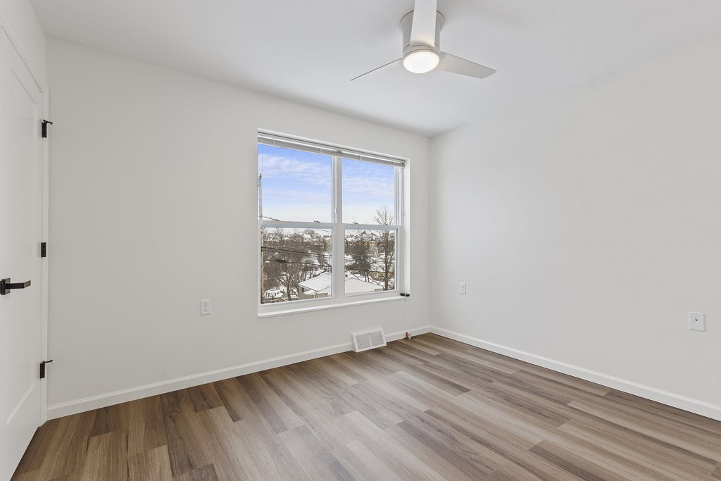 an empty living room with hardwood floors and a large window