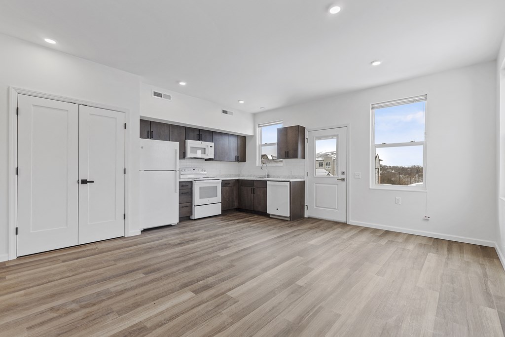 an open kitchen and living room with white walls and wooden floors