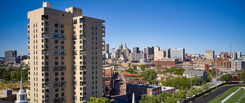 A tall building with many windows is in the foreground of a cityscape.
