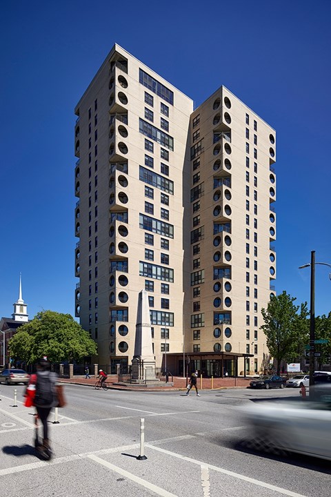 A tall building with circular windows is located on a street corner.
