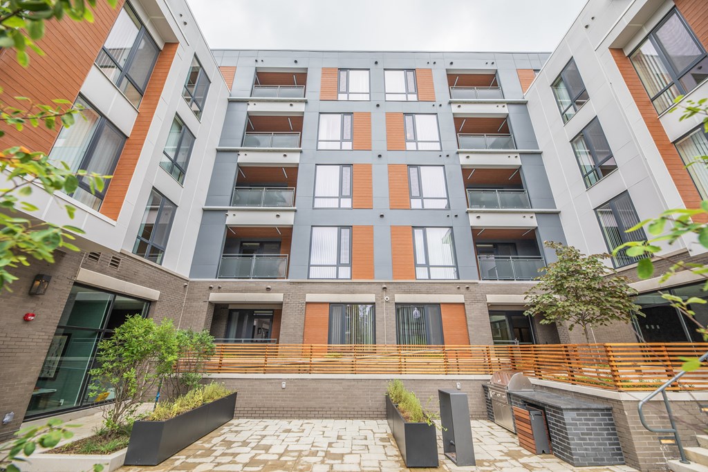 A modern apartment building with a courtyard and plants.