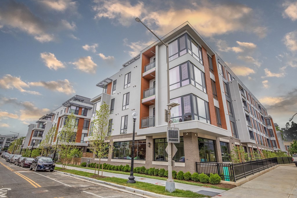 A modern apartment building with a parking lot in front.