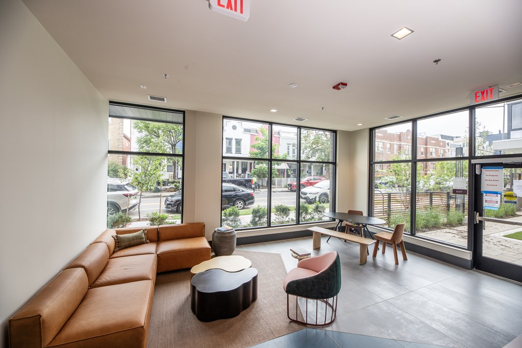 A large room with a brown couch and a table in front of a window.
