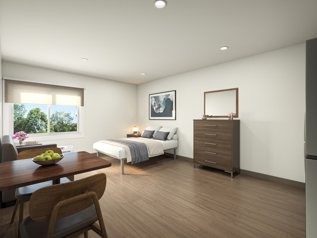 A bedroom with a bed, dresser, and table.