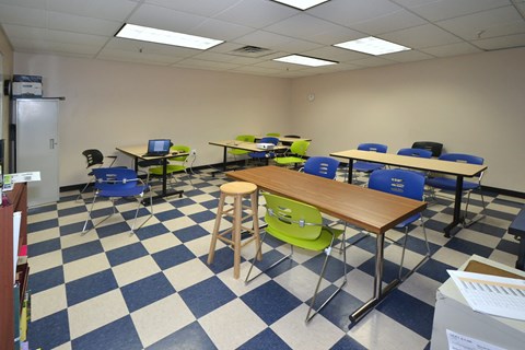 A classroom with blue and white checkered floor and tables with chairs.