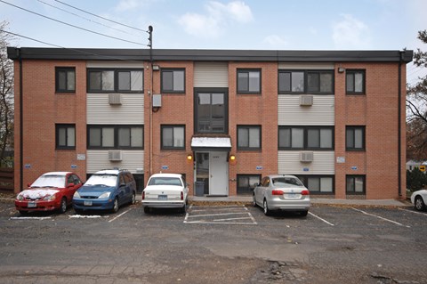 A parking lot with cars in front of a brick building.