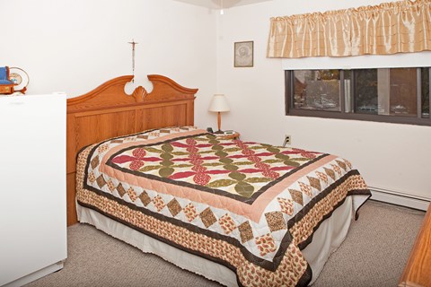 A bed with a quilt on it in a bedroom.