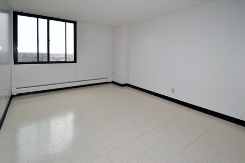 A large empty room with a window overlooking a cityscape.