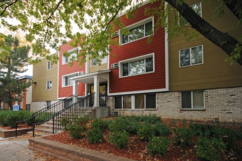 A red and beige building with a black railing on the steps.