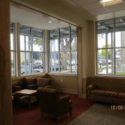 A brown couch and chairs are in a room with large windows.