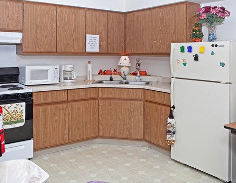 A kitchen with a white fridge and wooden cabinets.