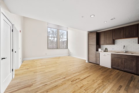 an empty kitchen and living room with wood flooring and a window
