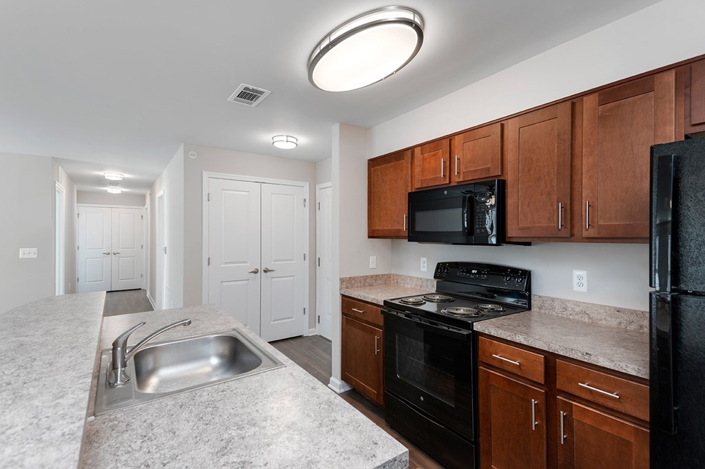 A kitchen with black appliances and brown cabinets.