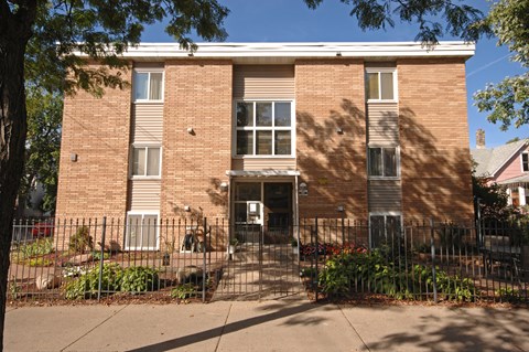 A brown brick building with a black gate in front.