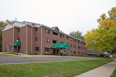 A red brick building with a green awning and an American flag on the roof.