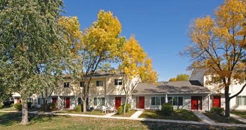 A row of houses with trees in front of them.