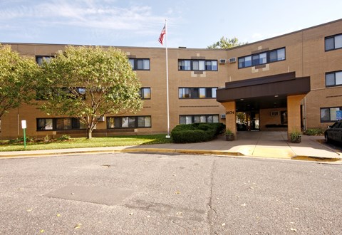 A building with a flag on top and a tree in front.