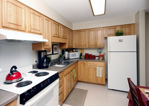 A kitchen with wooden cabinets and a red stove top.