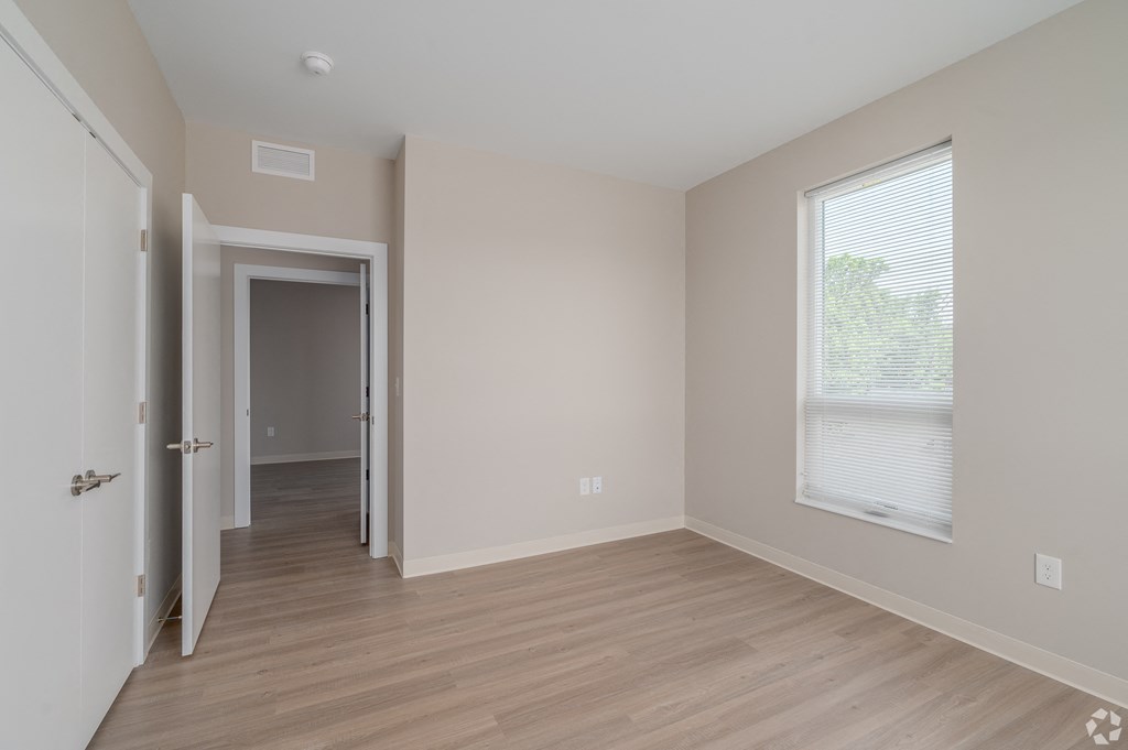 an empty bedroom with hardwood flooring and a large window