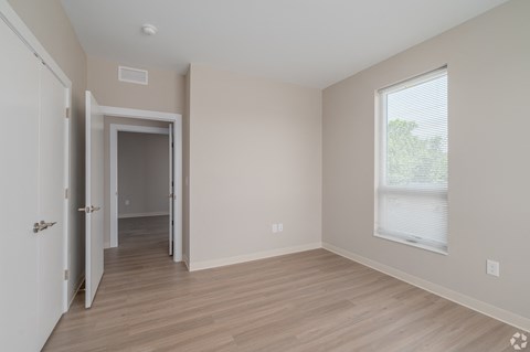 an empty bedroom with hardwood flooring and a large window