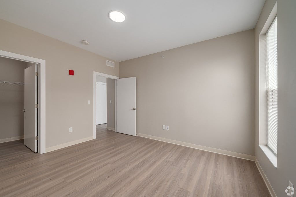 an empty living room with wood flooring and a door to a closet