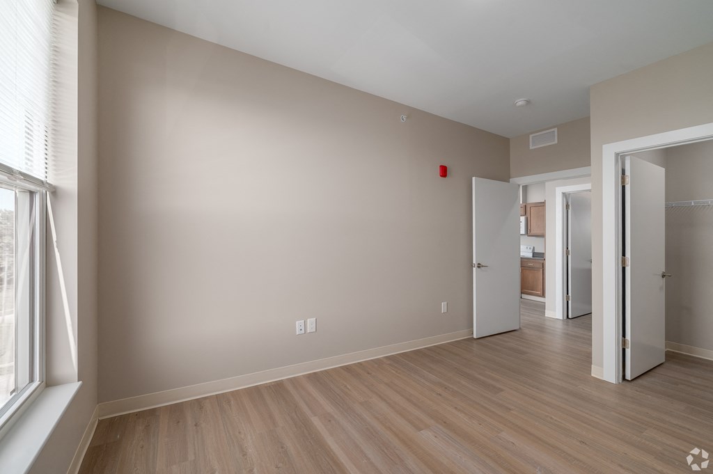 an empty living room with wood flooring and a door to a hallway