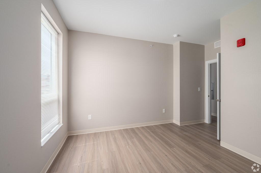 an empty living room with a large window and wood flooring