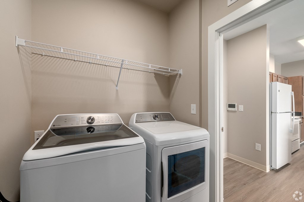 an empty laundry room with two washes and a dryer in front of a