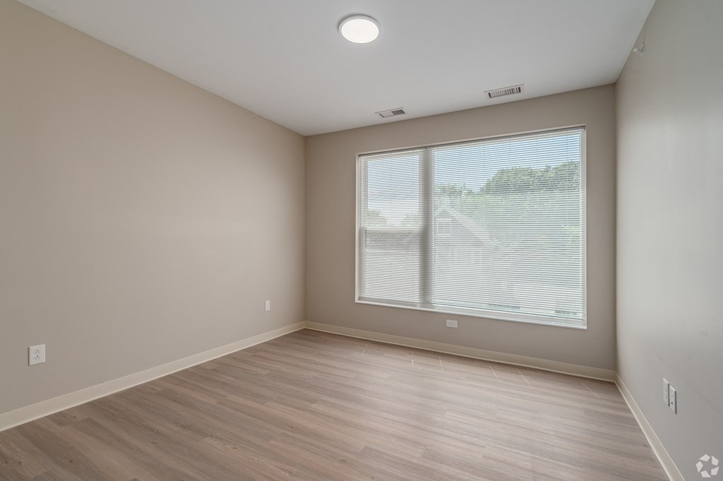 an empty living room with a large window and wood flooring