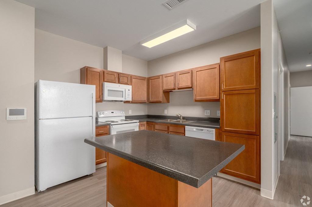 a kitchen with white appliances and wooden cabinets and a black counter top