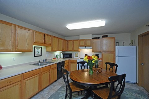 A kitchen with wooden cabinets and a table with chairs.