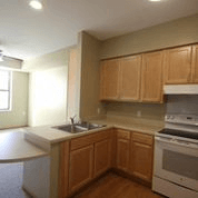 A kitchen with wooden cabinets and a white counter top.
