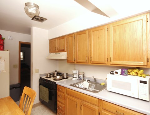 A kitchen with wooden cabinets and a white microwave.