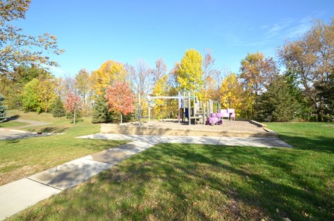 A park with a playground and trees in autumn colors.