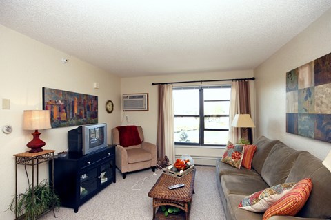 A living room with a brown couch, a black dresser, a red lamp, and a painting on the wall.