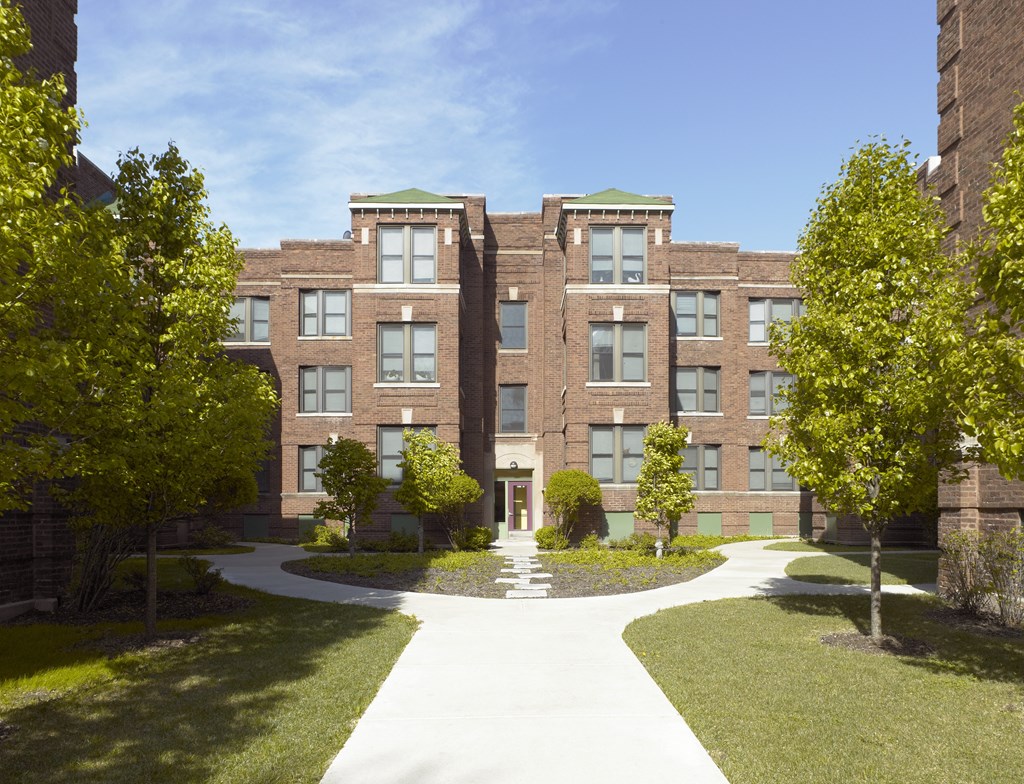 A large building with a green roof and a walkway in front.