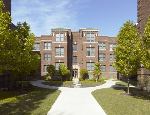 A large building with a green roof and a walkway in front.