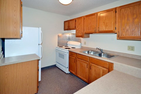 A kitchen with a white refrigerator, white stove, and brown cabinets.