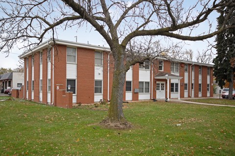A red brick building with a tree in front.