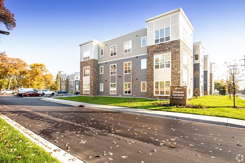 A modern apartment building with a parking lot in front.