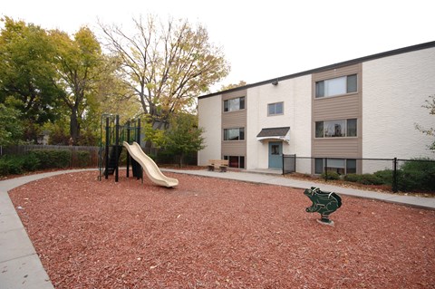 A playground with a slide and a green frog statue.