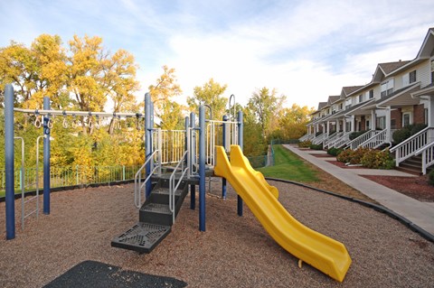 A playground with a yellow slide and a metal structure.