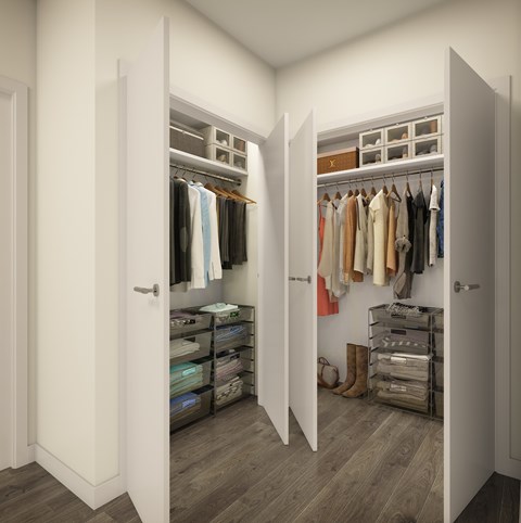 A walk in closet with clothes hanging and shelves.